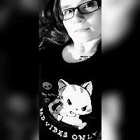 A black and white photo of Alice in a top with a cartoon cat that says 'bad vibes only'
