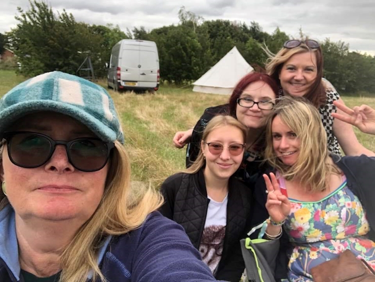 Five women pose for a selfie in a camping field